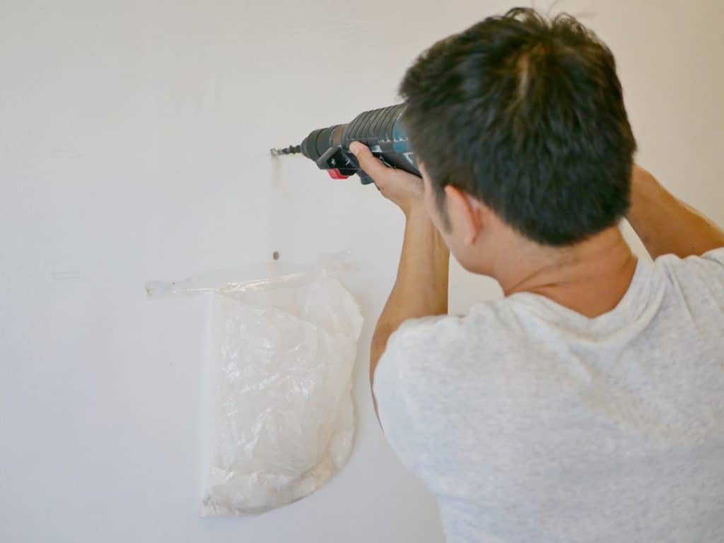 Man drilling into concrete wall to hang a picture