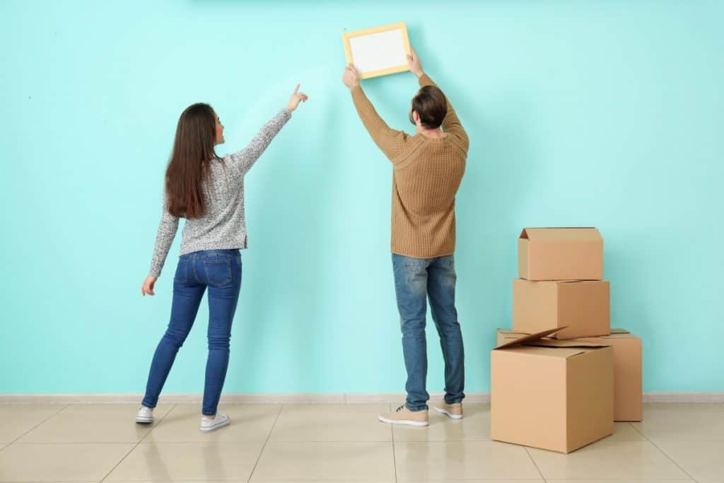 Couple choosing where to hang a picture on a concrete wall