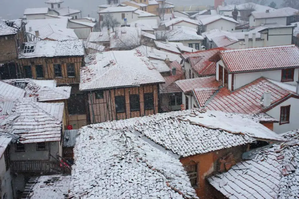 Houses with concrete roof tiles covered in snow.