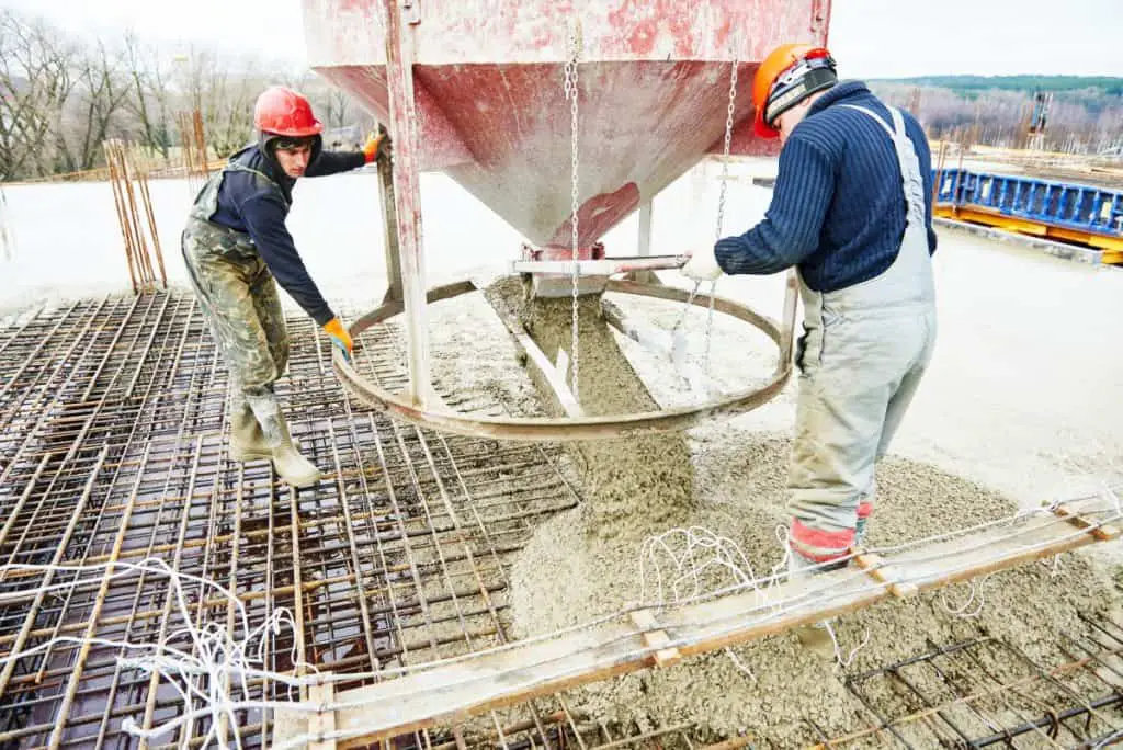 Two workers pouring concrete