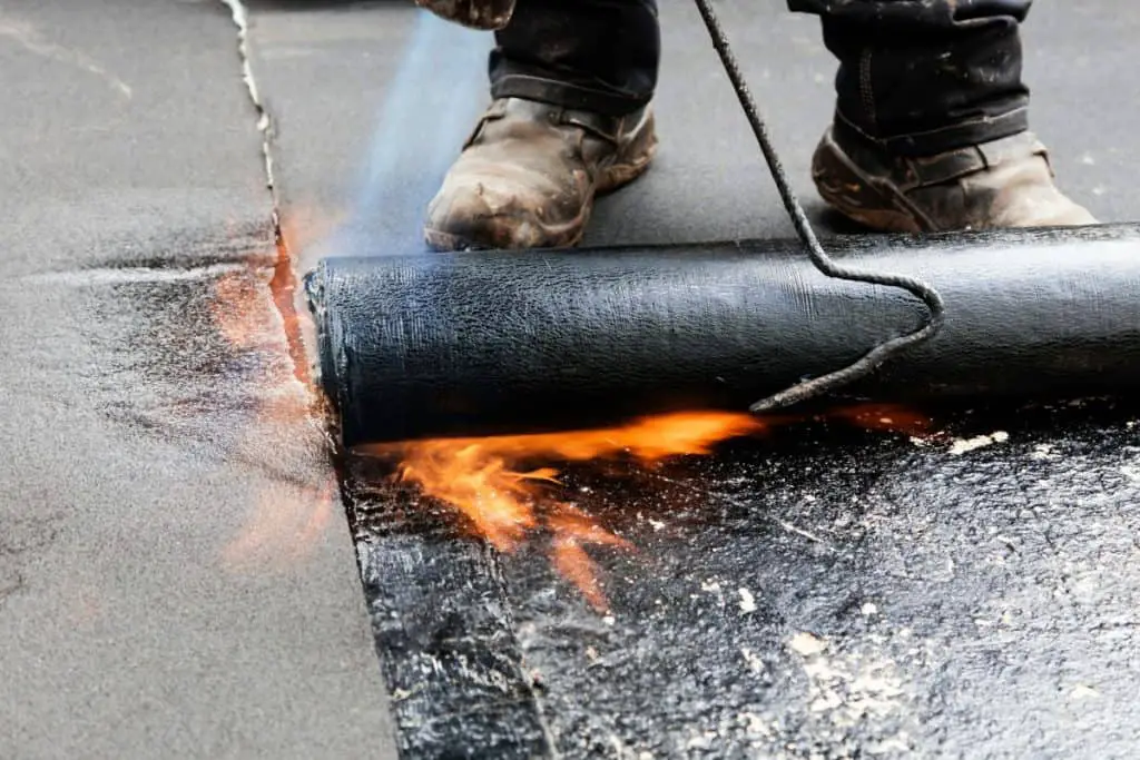 Asphalt (bitumen) being melted onto a flat roof as a waterproof base.