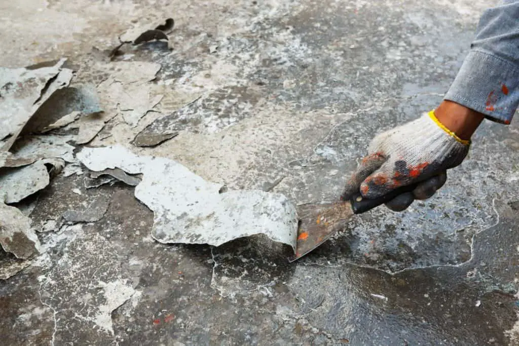 Preparing concrete floor for acid staining by scraping off old paint.