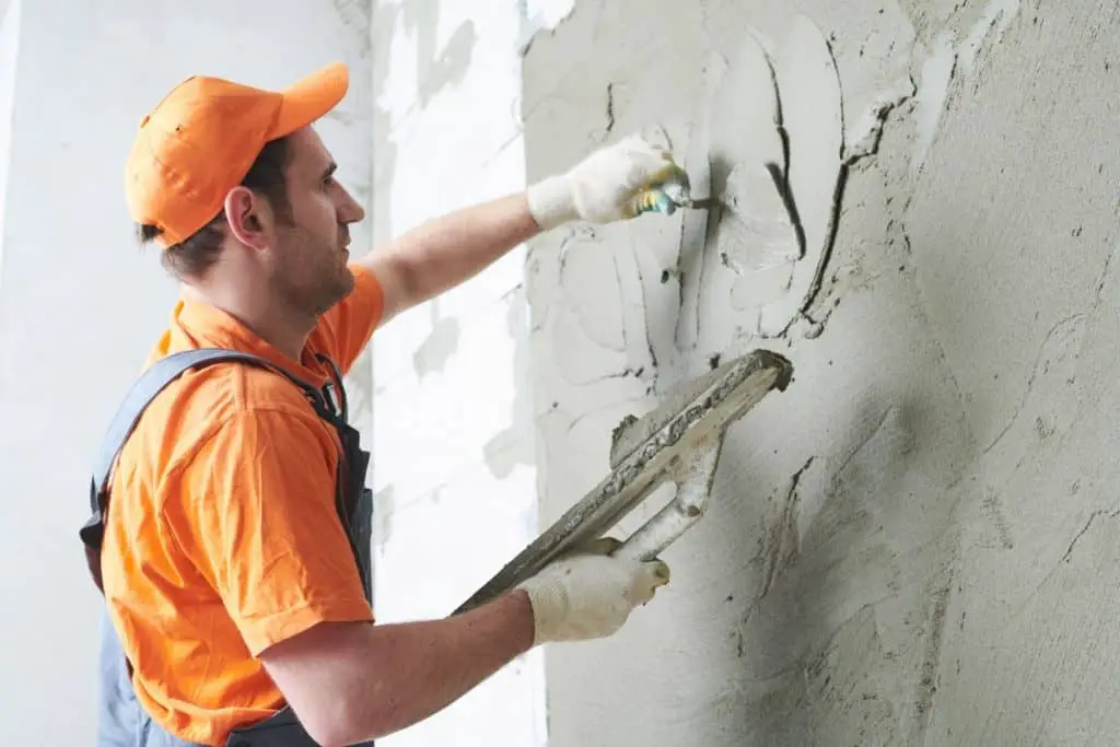 Man parging a concrete wall to cover it.