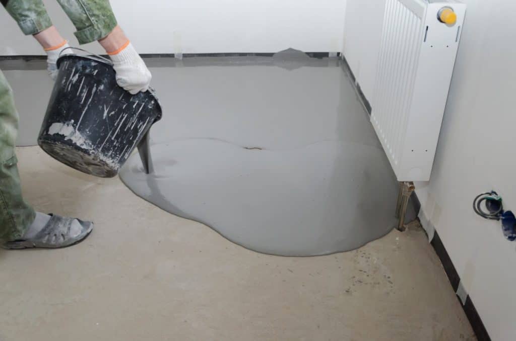 Man pouring self-leveling concrete on floor