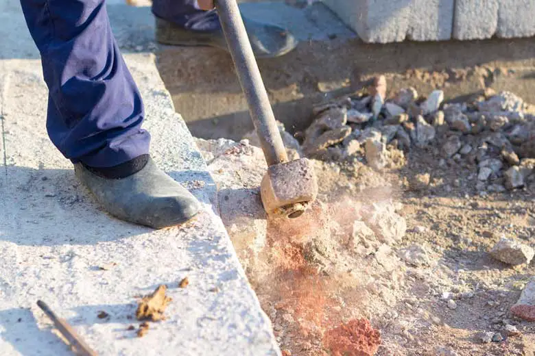 Man breaking up concrete steps with a sledgehammer