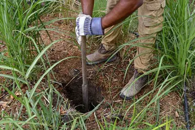 Man digging hole to set pole in concrete